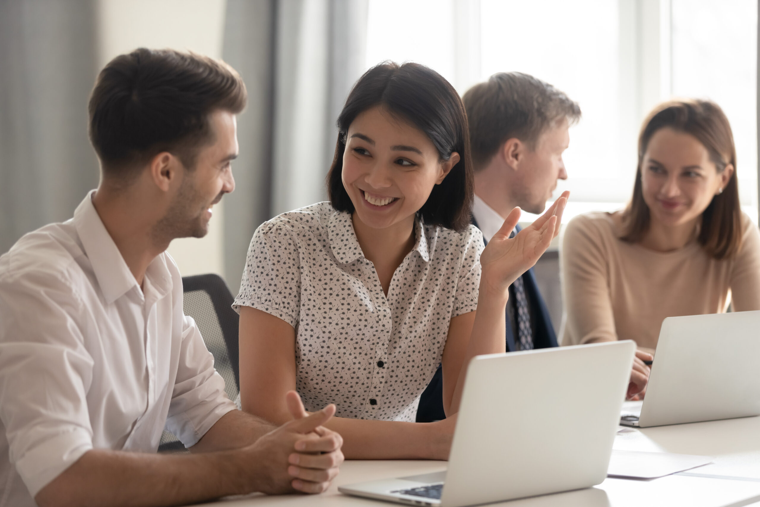 Happy friendly diverse employees talking laughing working together discussing good news