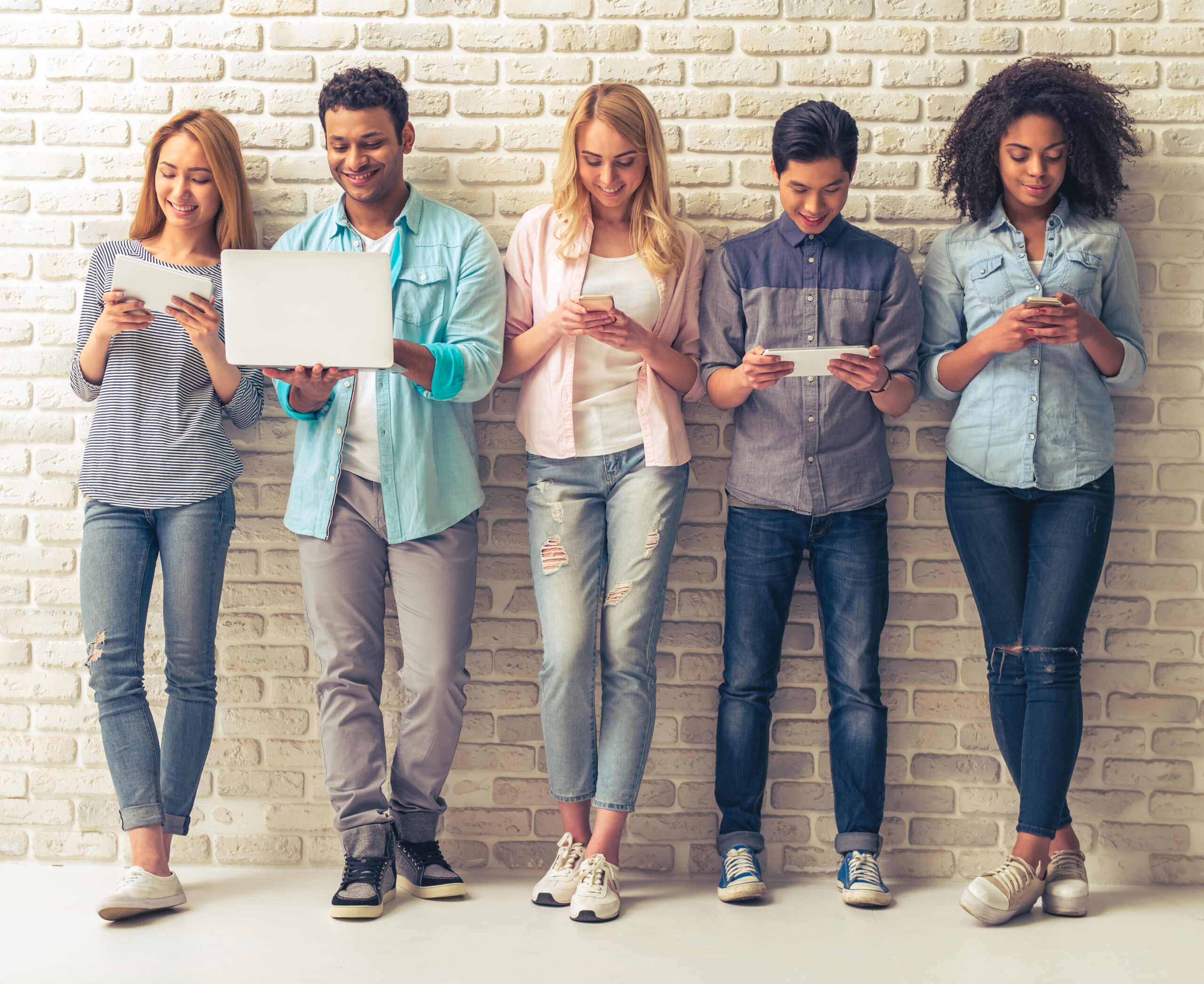Beautiful young people of different nationalities are using gadgets and smiling,